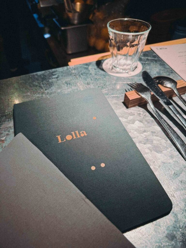 Close-up of Lolla Singapore restaurant menu with copper text and cutlery.