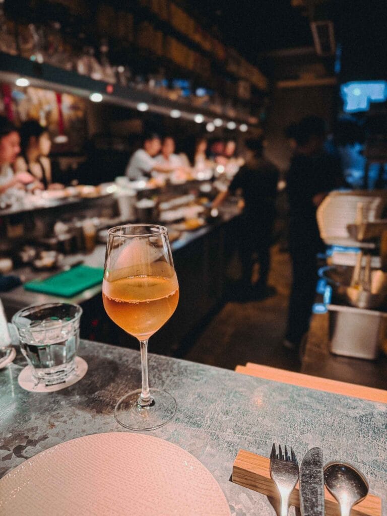 Wine glass with an orange-hued drink (Le Paradou) on Lolla Singapore counter.
