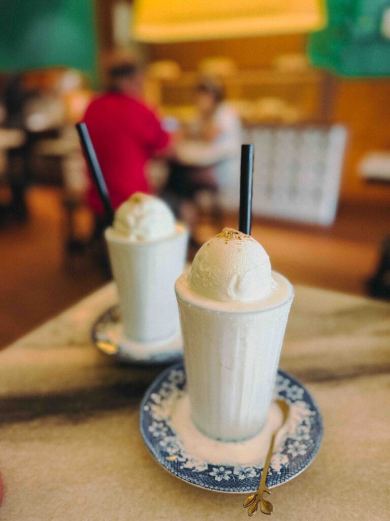Two Coconut Breeze Shakes topped with coconut ice cream on blue floral saucers at Nenek Johor Bahru