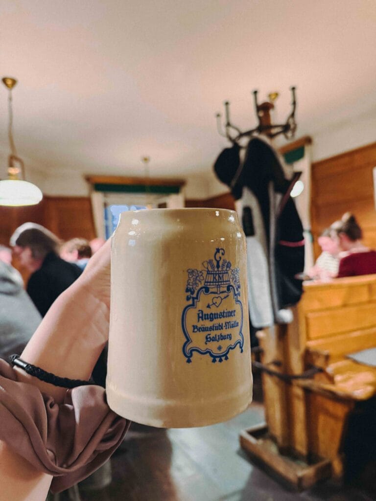 A frosty glass of golden Augustiner Bräu Salzburg Lager beer on a wooden table inside the rustic Bärenwirt restaurant.