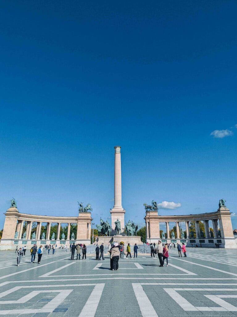 The majestic Heroes' Square (Hősök tere) in Budapest, featuring the Millennium Monument with the Archangel Gabriel on top, and the two colonnades behind it.
