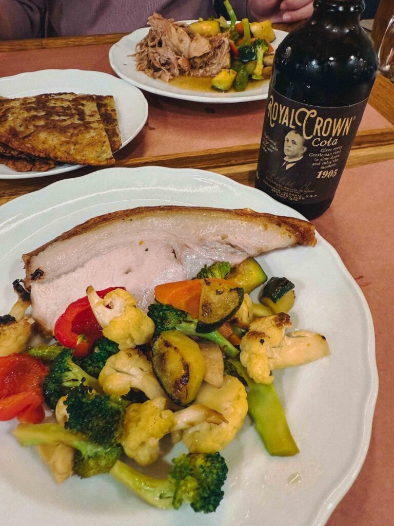 A tray of assorted roasted Czech meats and seasonal vegetables served with a crispy garlic potato pancake (bramborák).