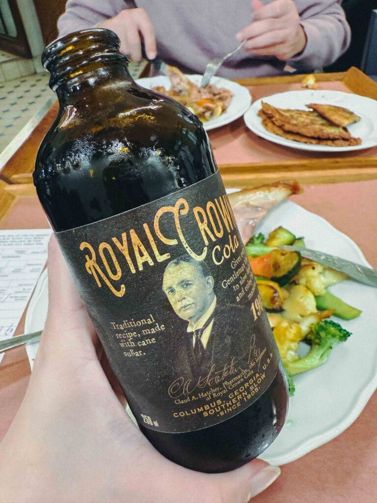 A chilled glass bottle of Royal Crown (RC) Cola sitting on a wooden table at a Prague restaurant.