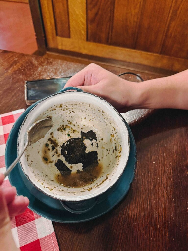 A hearty, traditional Czech dish (likely a goulash or stew) served in a rustic, dark bowl at Pilsen Restaurant in Prague, surrounded by side dishes including dumplings.