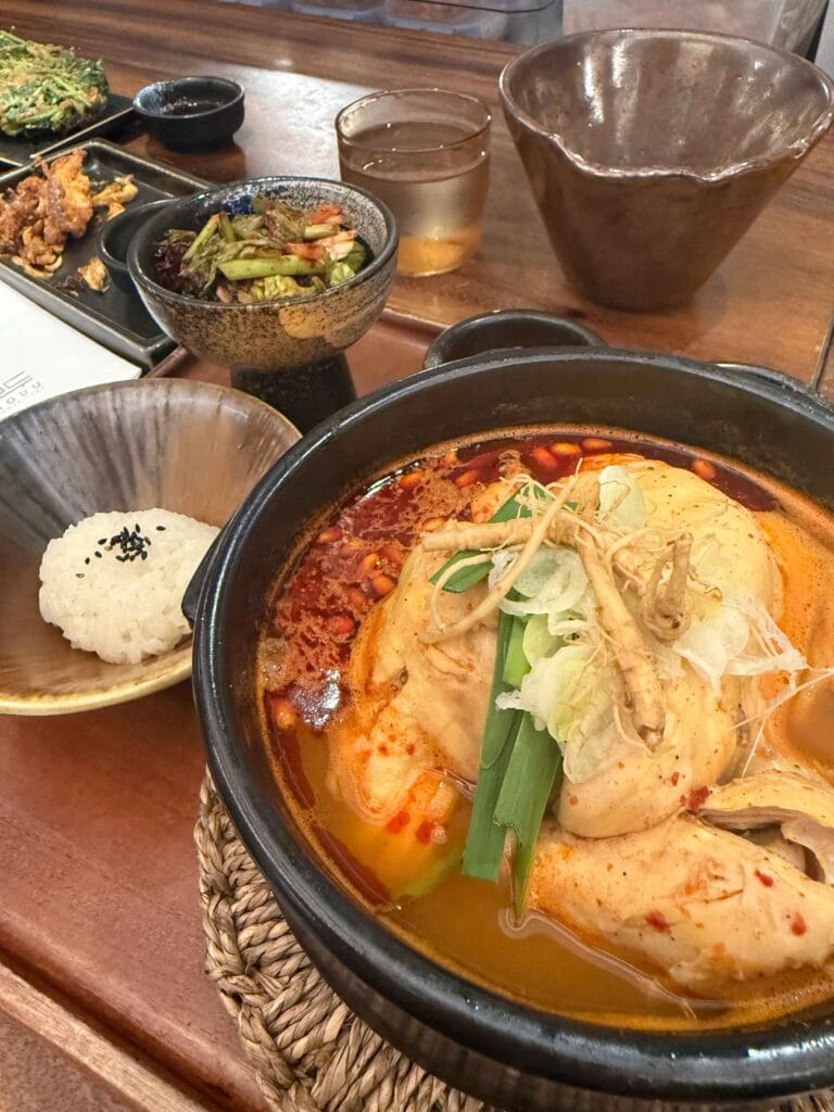Hangover samgyetang in spicy red broth with ginseng, scallion and side dishes at MODU Samgyetang Singapore