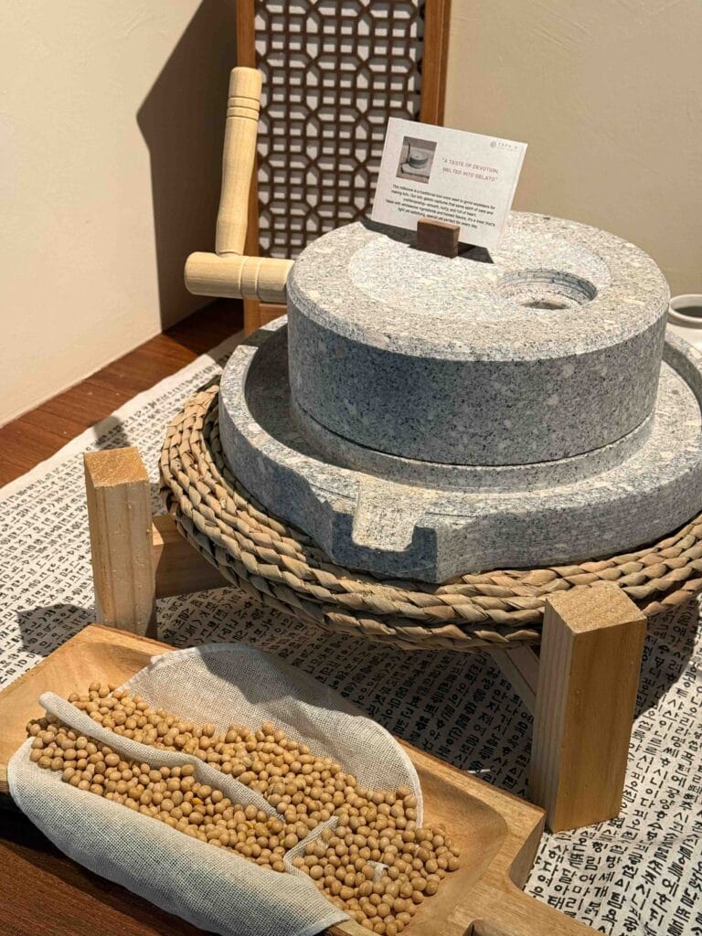 Stone grinding mill with a tray of soybeans on display at Tofu G Gelato in Mandarin Gallery