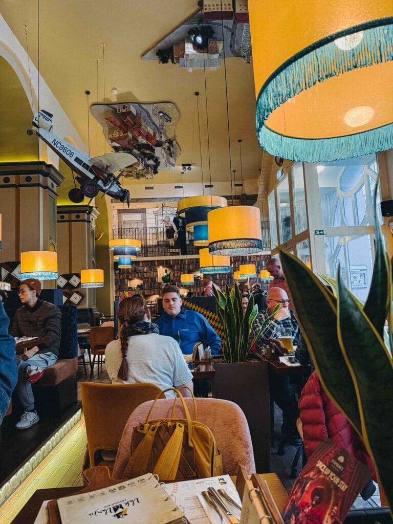 A view of the warm and inviting interior seating area at VakVarjú restaurant in Budapest, featuring wooden tables, modern chairs, and atmospheric lighting.