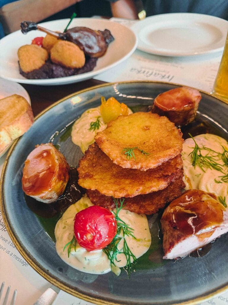 Pork tenderloin wrapped in cured ham, served with a crispy potato rösti, chilled squash stew, and vibrant green dill oil.