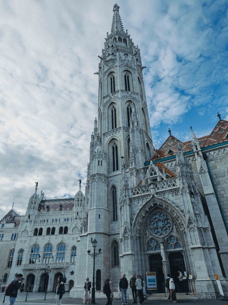 The colorful, diamond-patterned tile roof and ornate Gothic tower of the Church of Our Lady of Buda Castle (Matthias Church) in Budapest.