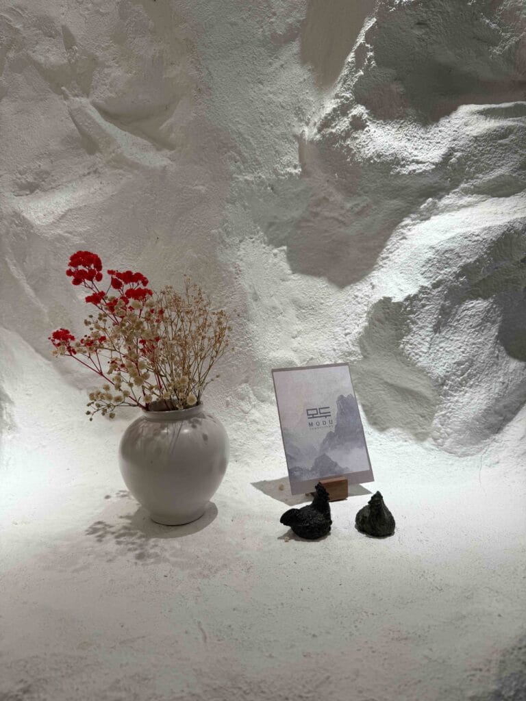 Vase of dried flowers, MODU menu card and two small black chicken figurines at MODU Samgyetang Singapore