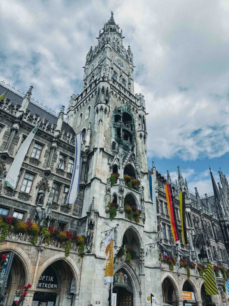 A panoramic view of the intricate Neo-Gothic façade of the Neues Rathaus in Munich, featuring its tall tower and the famous Rathaus-Glockenspiel.