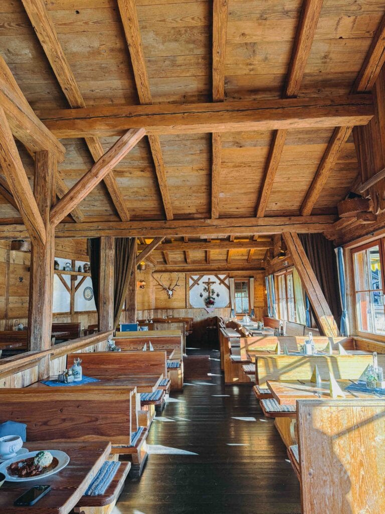 The cozy, wood-paneled interior of Dorf-Alm restaurant in St. Wolfgang, featuring traditional Austrian alpine decor and heavy timber beams.