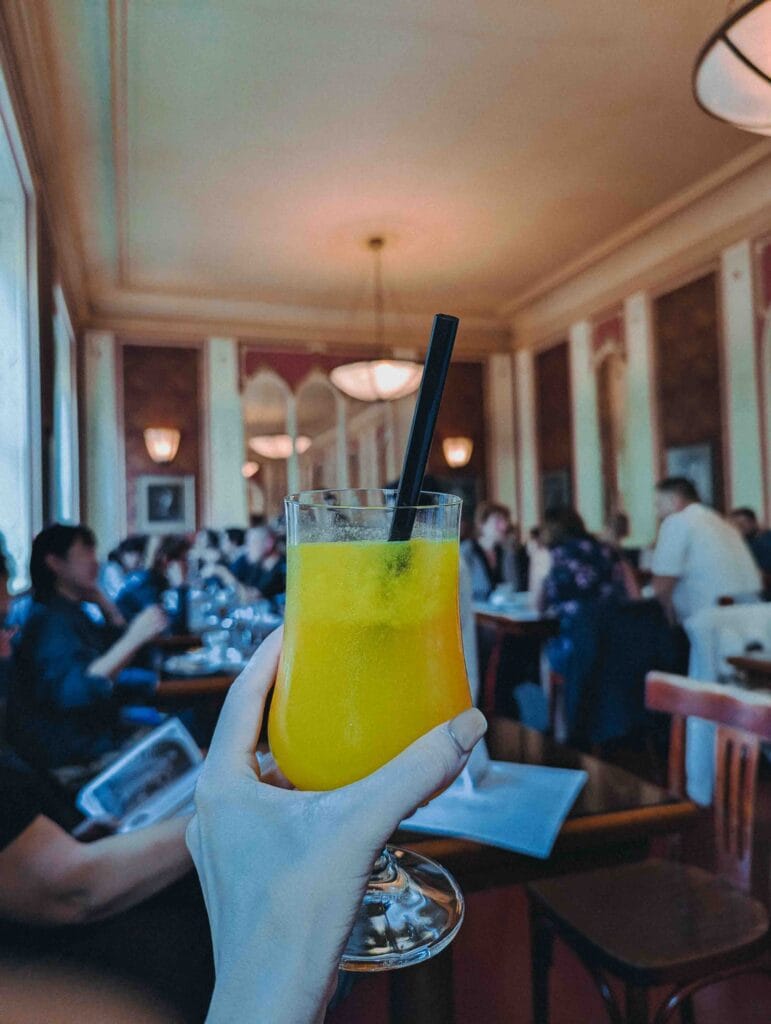 A unique, branded Orangina glass bottle served on a wooden tray, featuring the distinct textured glass and bottle shape.