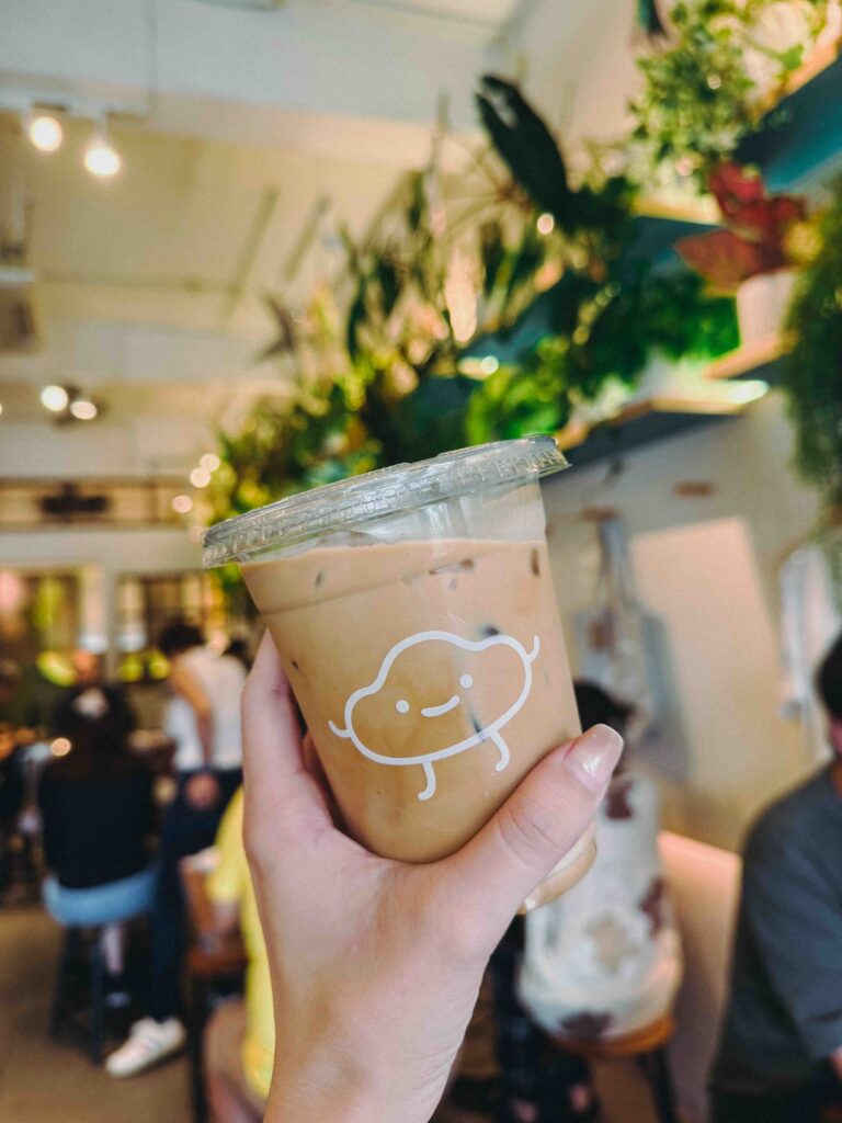 Hand holding a cold latte with the Fluffed Cafe logo in Petaling Jaya