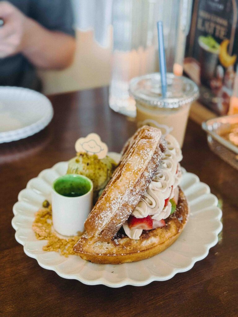 Full plate of the Pinocchio waffle with pistachio ice cream and iced latte at Fluffed Cafe Petaling Jaya