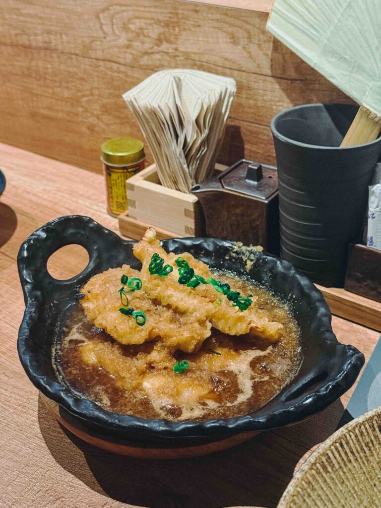 Mizore-ni chicken tempura in dashi hot pot served in a black ceramic pot at LILYAN Singapore