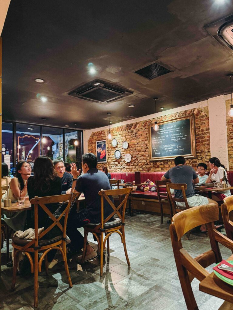 Diners seated at My Little Spanish Place Singapore with exposed brick walls and chalkboard menu