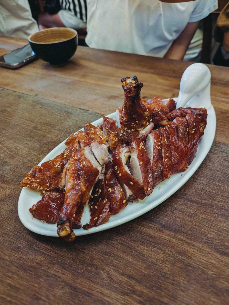 Half roasted duck with lacquered crispy skin and sesame seeds sliced and served on a white platter at Cơm Linh Hội An