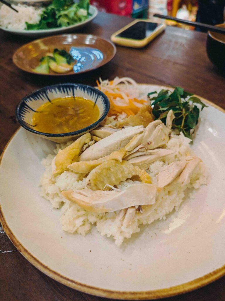 Hội An chicken rice with shredded poached chicken over fragrant rice served with turmeric dipping sauce and pickled vegetables at Cơm Linh