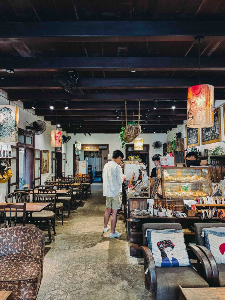 Dudu Cafe Hoi An interior with dark wooden beams vintage tile floors hanging pendant lamps pastry display case and antique furniture