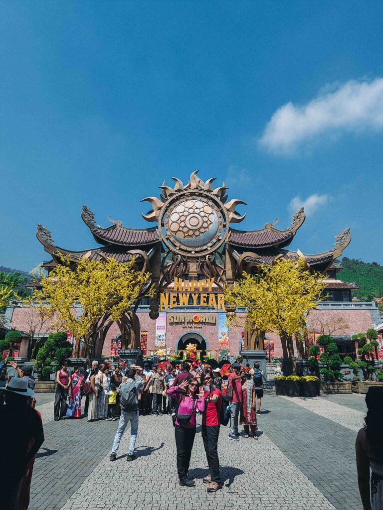 Ba Na Hills Sun World entrance gate decorated for Chinese New Year with yellow blossom trees and crowds in Da Nang