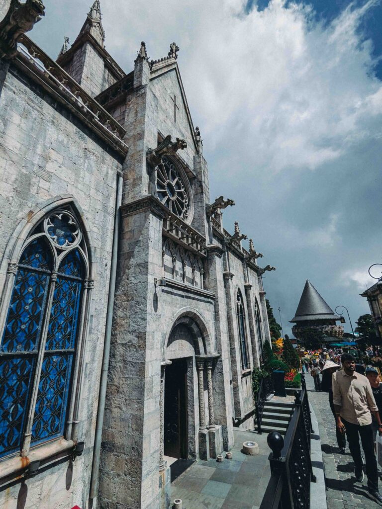 Gothic-style stone church with rose window and blue stained glass in the French Village at Ba Na Hills Da Nang