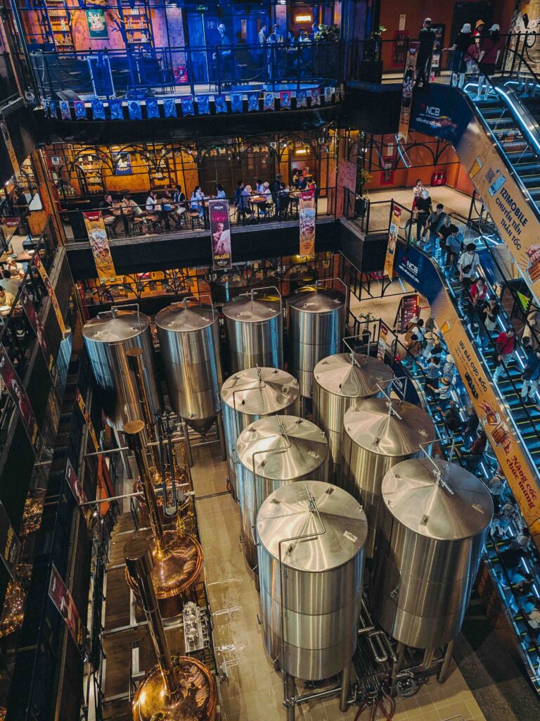 Aerial view of Bana Brew House interior at Ba Na Hills with large stainless steel brewing tanks and multi-level dining area