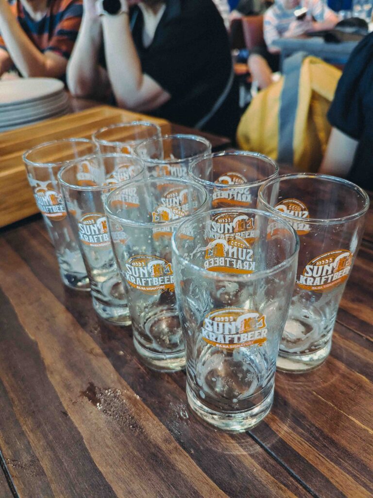 Multiple Sun Kraftbeer branded pint glasses lined up on a wooden table at Bana Brew House Ba Na Hills