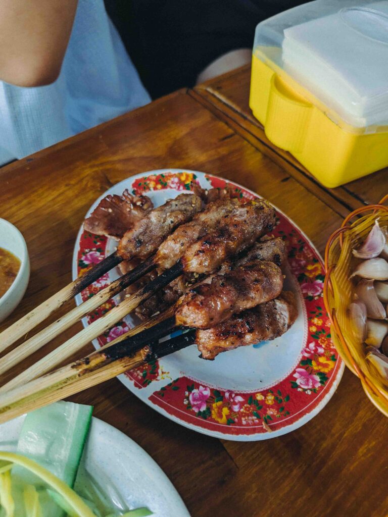Grilled nem nuong skewers served on a plate at Quán Phú Hồng Da Nang