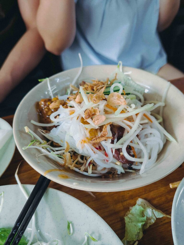 Bowl of bun thit nuong barbecue noodles topped with herbs and peanuts at Quán Phú Hồng