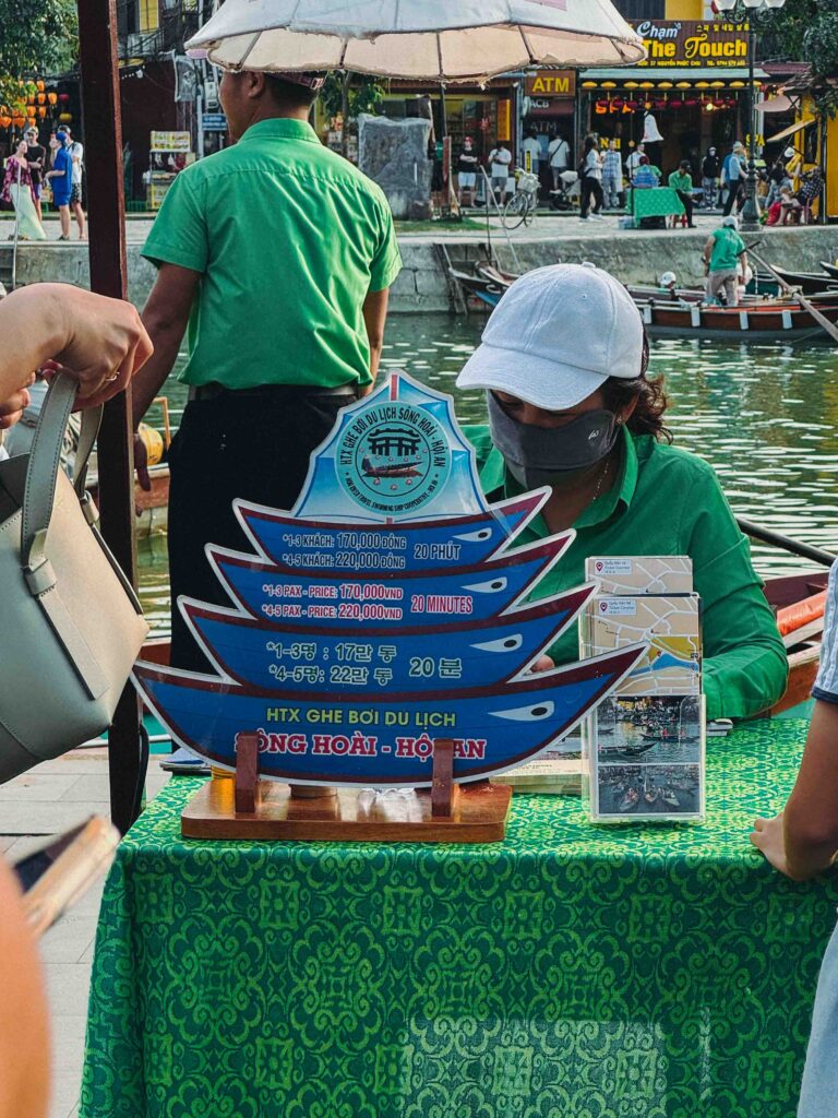 Boat-shaped sign showing lantern boat ticket prices in Vietnamese dong at the official Thu Bon River counter in Hoi An showing 170000 VND for 1-3 passengers
