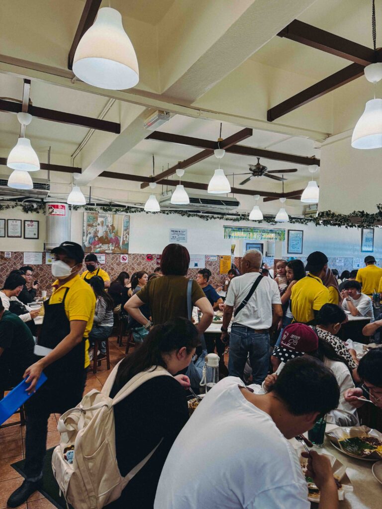 Busy interior dining hall at Village Park Restaurant Petaling Jaya packed with diners and staff in yellow uniforms
