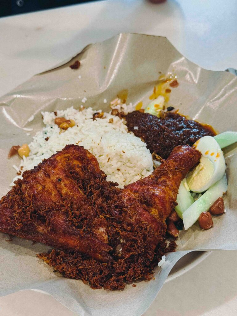 Nasi Lemak Ayam Goreng at Village Park Restaurant with fragrant coconut rice, crispy fried chicken, dark sambal, half boiled egg, peanuts, and cucumber
