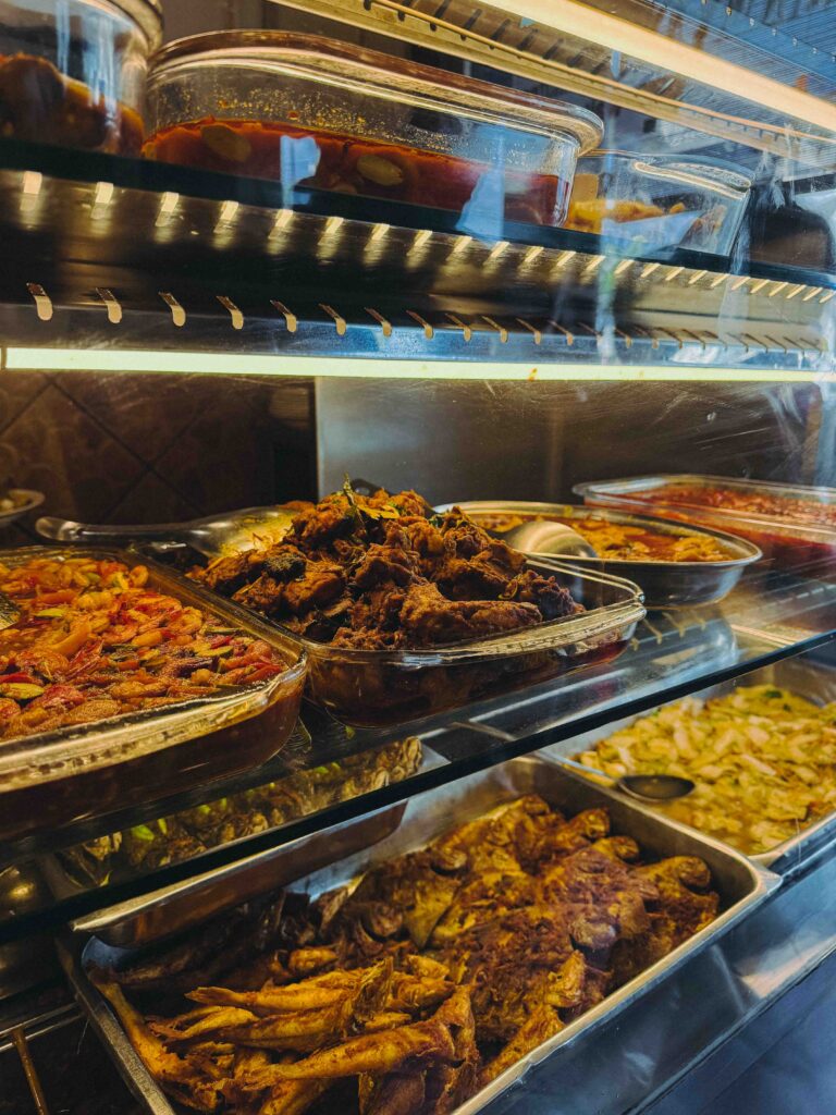 Close-up of Village Park Restaurant lauk display with rendang, prawns, and fried chicken options